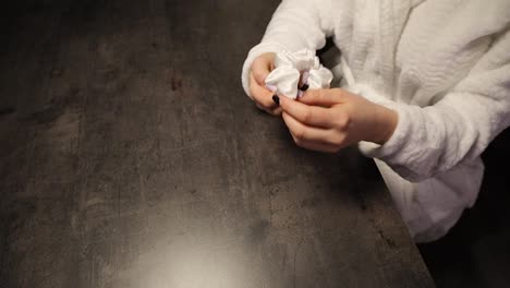 young beautiful woman takes a scrunchie from the table top and ties her her while posing