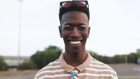 happy gay african man with make-up smiling on camera outdoor