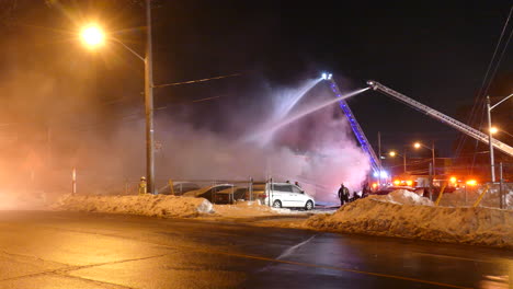 vista estática de bomberos e hidrantes trabajando para apagar un incendio, en medio de un camino nevado