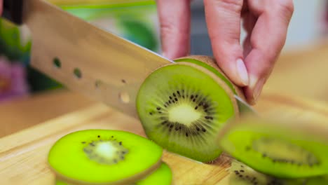 women's hands housewives cut with a knife fresh kiwi on the cutting board of the kitchen table