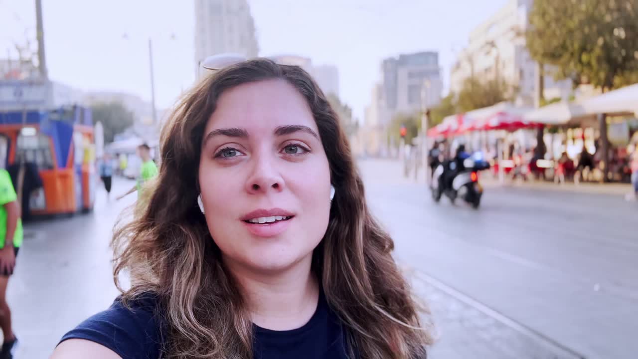 Influencer che realizza un vlog mentre cammina per una strada affollata della città