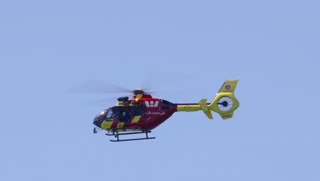 red and yellow helicopter flying in clear sky