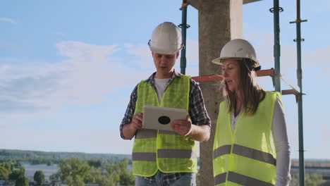 ingenieros profesionales con chalecos de seguridad y cascos que trabajan con tabletas digitales y planos