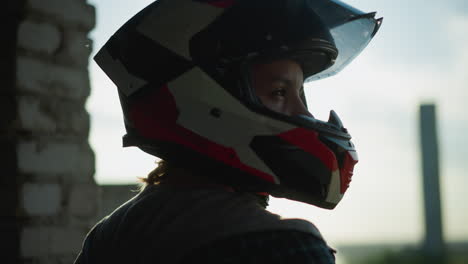 head view of a lady in a helmet, with sun rays reflecting through the visor as she gazes to the right