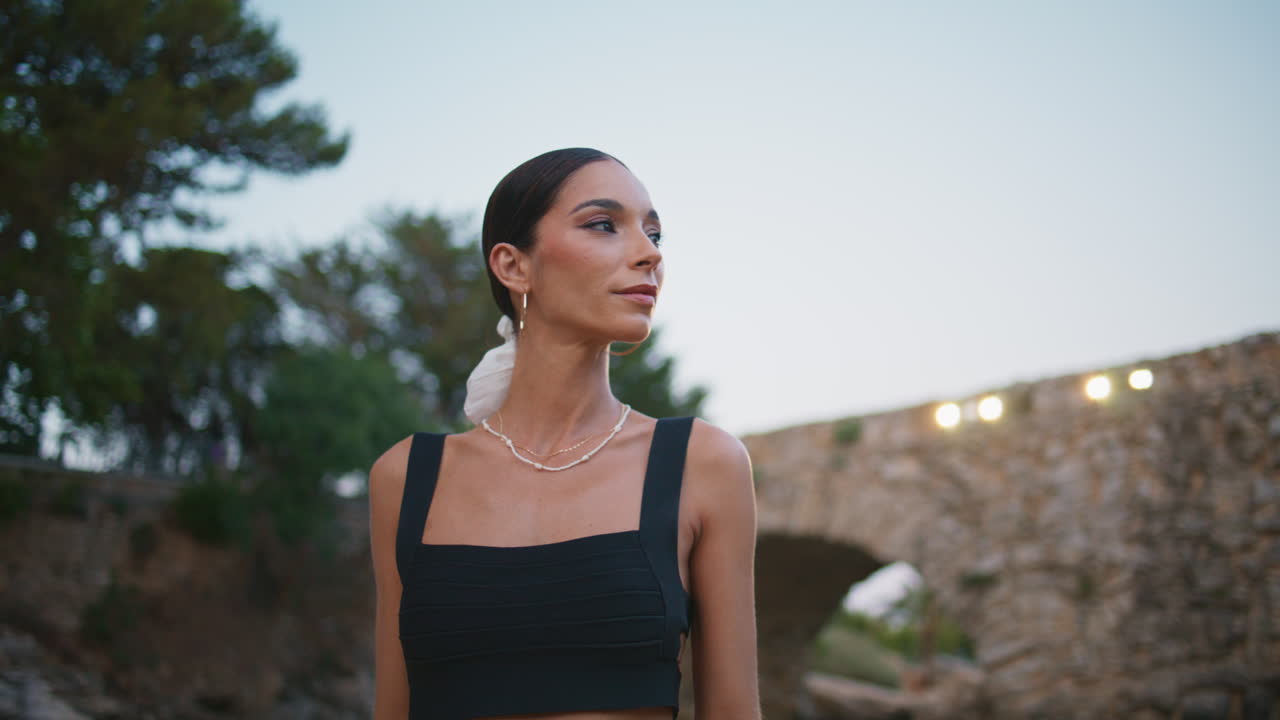 mujer elegante por un puente de piedra