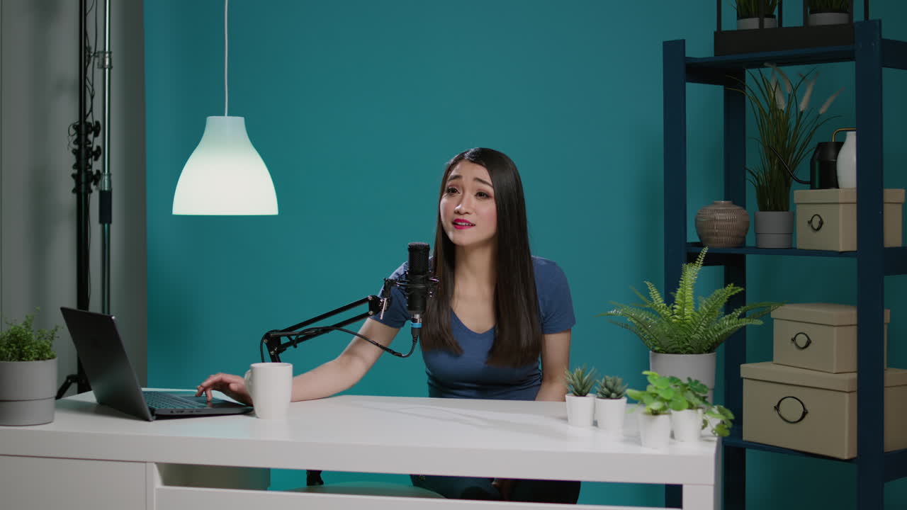 Donna asiatica registra un podcast online con microfono su fotocamera