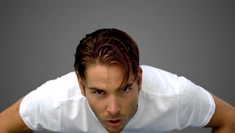 young sportsman doing push ups on grey background