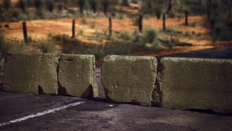 obstructed road with stone barriers in a rural desert landscape during daylight