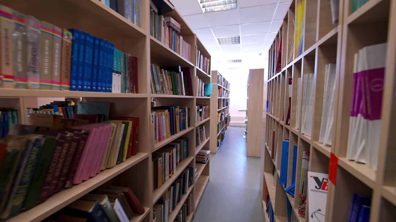 Wooden bookcases in the library. Different books on bookshelves inside the light library room. Education and knowledge concept.