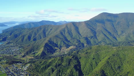 aerial drone shot of sea and town then panning to a mountainous forest