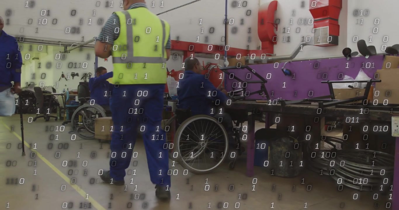 Seated chair worker working at bench while crew walking and pan causing data mask showing output