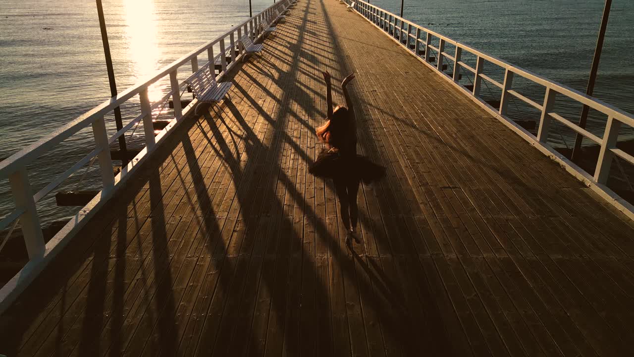 Woman dancer expressing ballet steps on beach pier at sunset