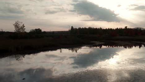 Flying-Over-The-Calm-Waters-Of-River-With-A-reflections-Of-Sky-During-Sunset-In-Magog,-Quebec,-Canada