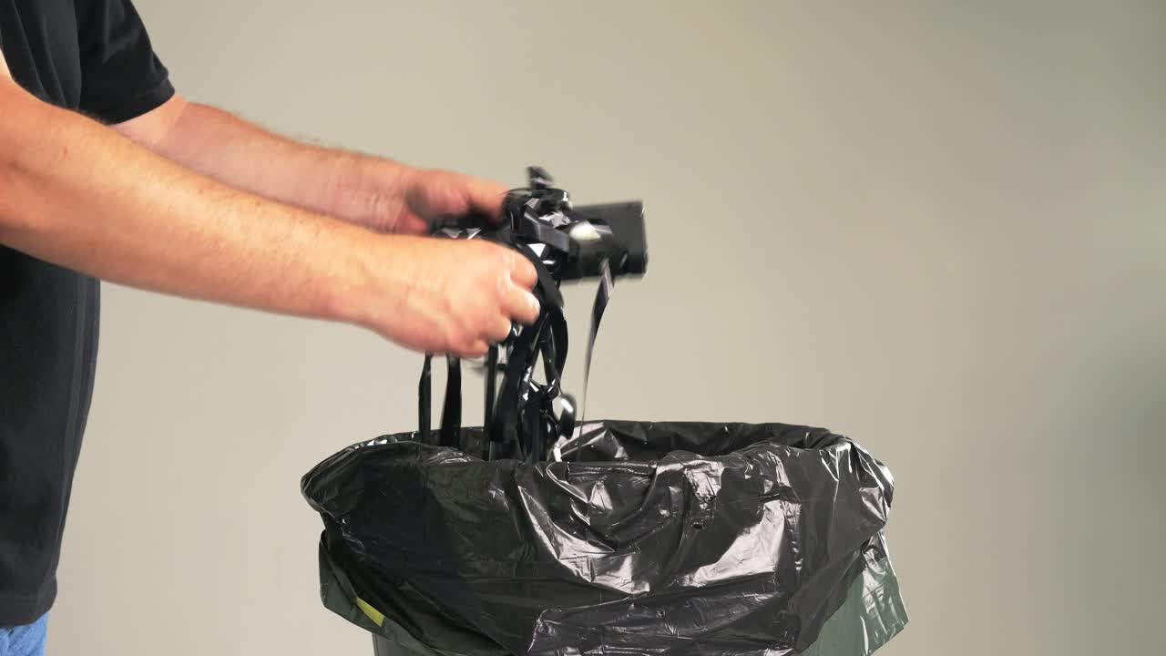 Un uomo sta gettando vecchie videocassette VHS usurate insieme alla cassetta nel bidone della spazzatura