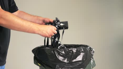 a man is throwing old worn-out vhs tapes along with the cassette into the garbage bin