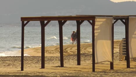 walking on a beach, two elderly women strolling on sandy shore, long shot