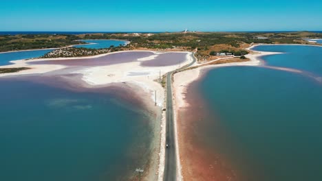 un dron disparado por encima de una bicicleta que viaja por un camino estrecho entre lagos en la isla de rotness en un día soleado, australia occidental