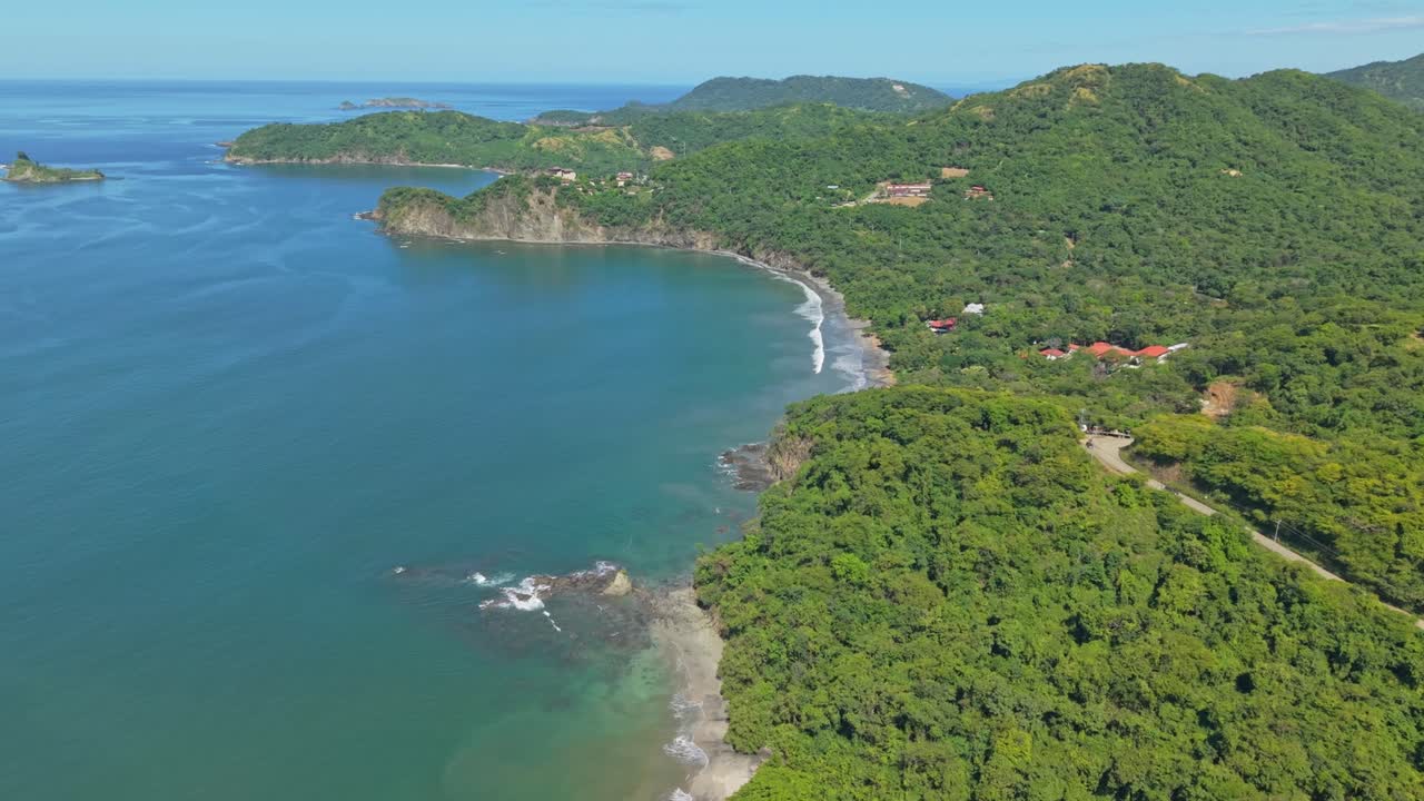Zoom in aerial view of Prieta Beach in Costa Rica surrounded by lush green hills and turquoise water.