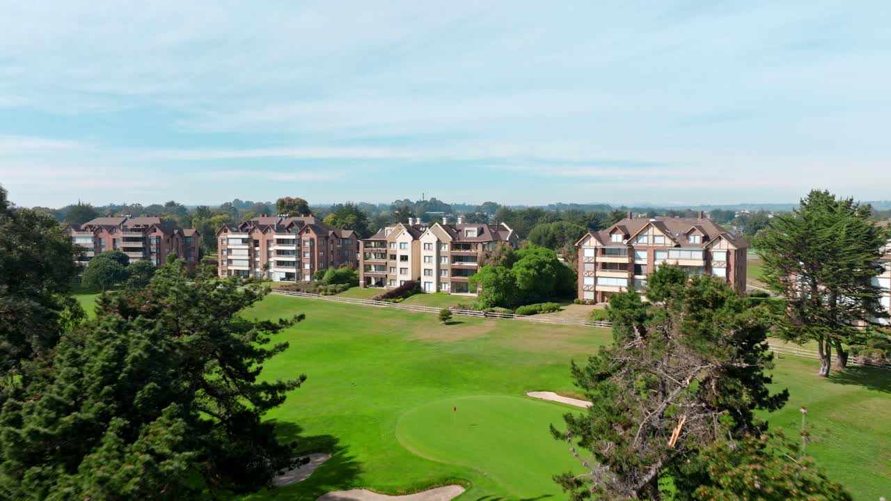 Dolly in aerial view of an exclusive condominium with its own golf course among trees