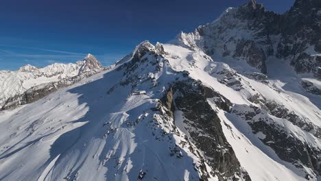 Impresionante-Vista-Aérea-De-Las-Crestas-Cubiertas-De-Nieve-De-Chamonix-Con-Pistas-De-Esquí-Grabadas-En-Las-Prístinas-Laderas-Blancas.