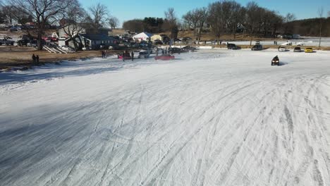 Atv-drifting-on-ice-and-snow-on-a-curbe-in-front-of-the-crowd-aerial-drone-4k-poynette-wisconsin