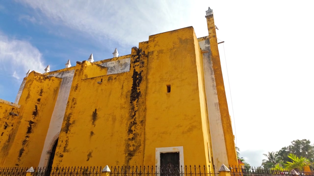 Le massicce mura giallo ocra del convento francescano del XVI secolo di Sant'Antonio da Padova si ergono contro un cielo luminoso a Izamal, la Città Gialla dello Yucatan, Messico, un punto di riferimento della regione.