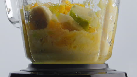 frutas frescas mezclando sacudidor en fondo blanco de cerca. ingredientes orgánicos.