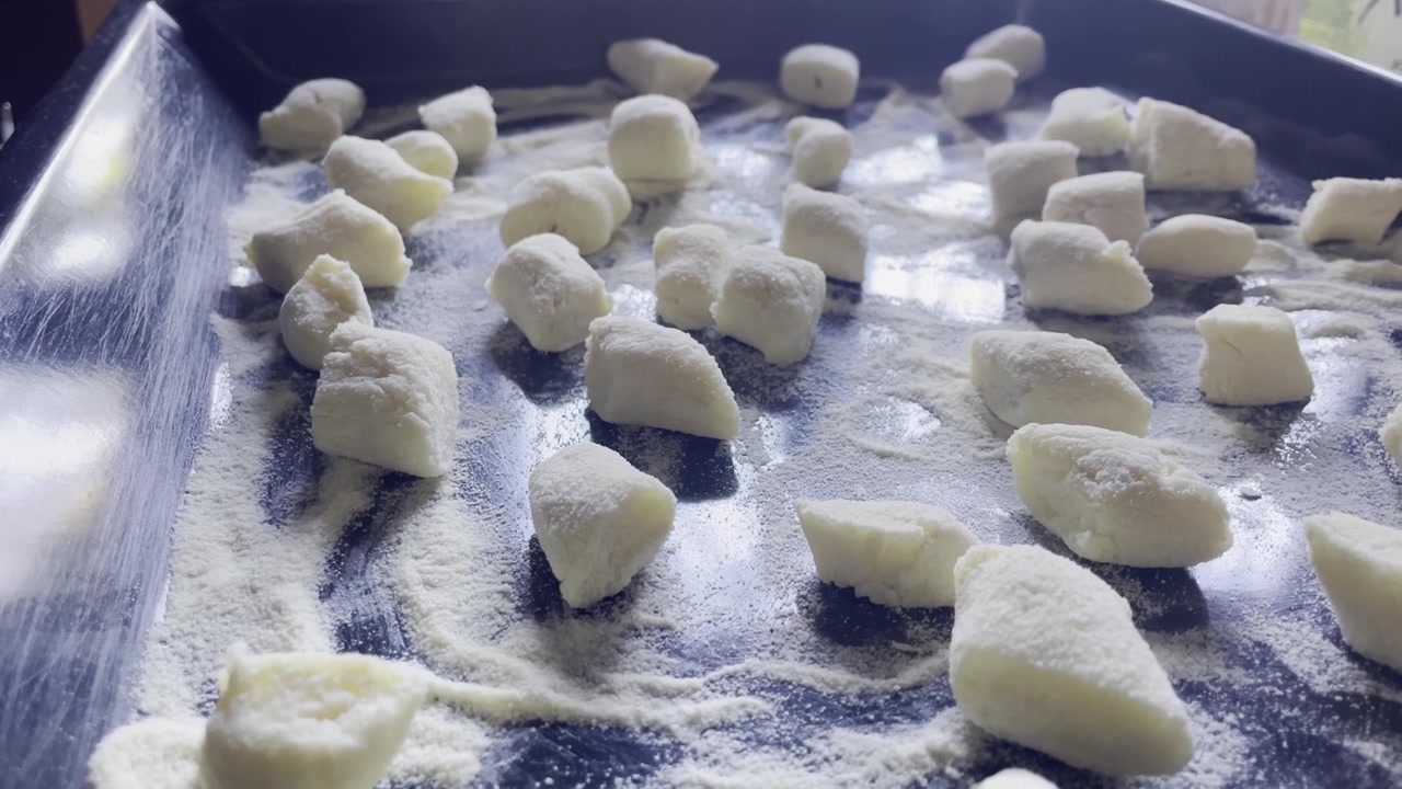 Primo piano di gnocchi crudi appena tagliati su una teglia infarinata, Italia