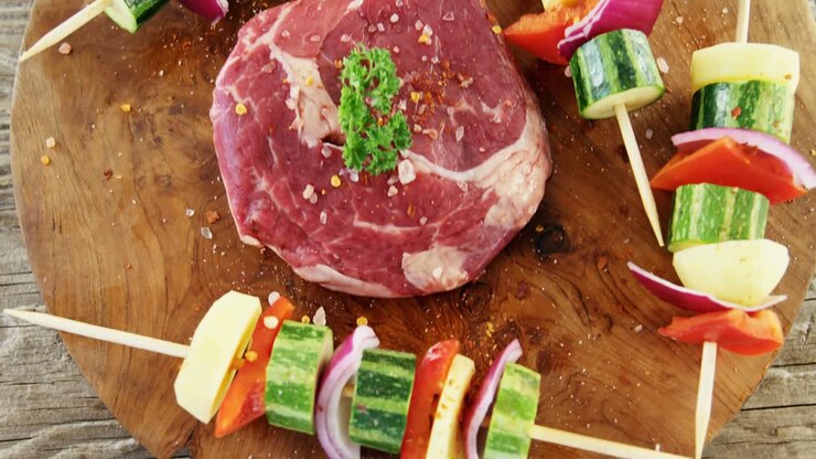 Steak marinasi dan sayuran tusuk di talenan kayu