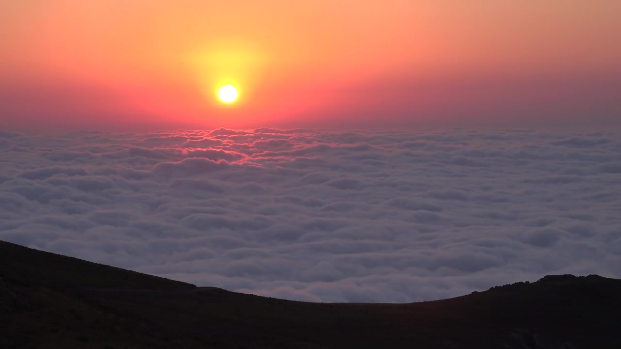 Atardecer sobre un mar de nubes desde la cima de una montaña.
