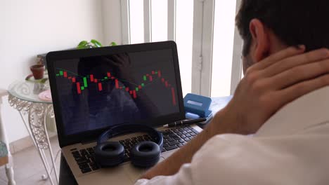 un hombre triste sacudiendo la cabeza mientras mira el gráfico de barras del mercado de valores financiero en una computadora portátil