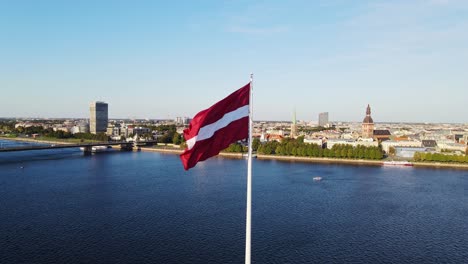 Latvian flag dominates peaceful river view in scenic drone shot over AB Dambis