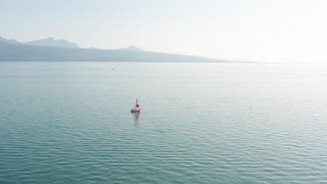 flying towards a small sail boat on a vast, blue lake