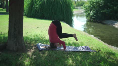 woman practicing supported headstand in park