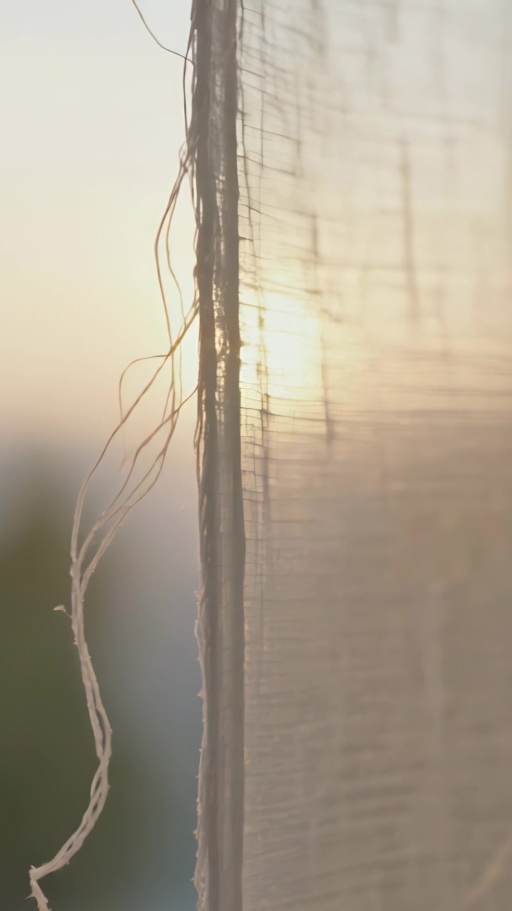 Video verticale: Bordo di una tenda velata che ondeggia reagendo al sole che sorge in casa, mostrando fili allentati