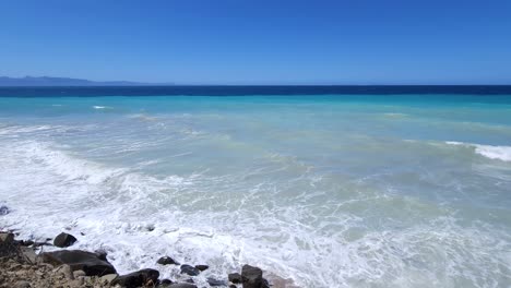 Tranquil-Mediterranean-Serenity:-Azure-Sea-and-White-Waves-Gently-Splash-on-Rocky-Shoreline-of-a-Quiet,-Secluded-Beach