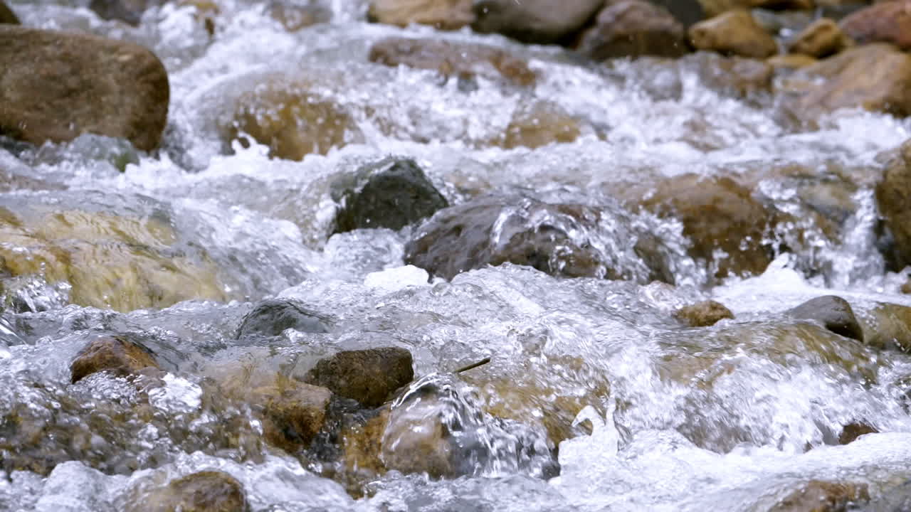 Clear stream running through stone boulders Abundant river flowing in slow motion