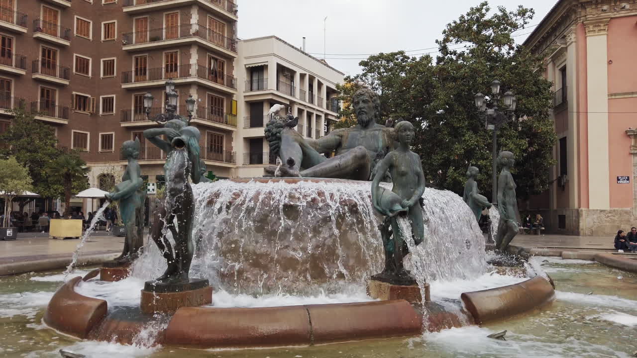 The enchanting fountain features sculptures and a flowing water display, situated in a bustling city square filled with cafes and shops, perfect for leisurely strolls