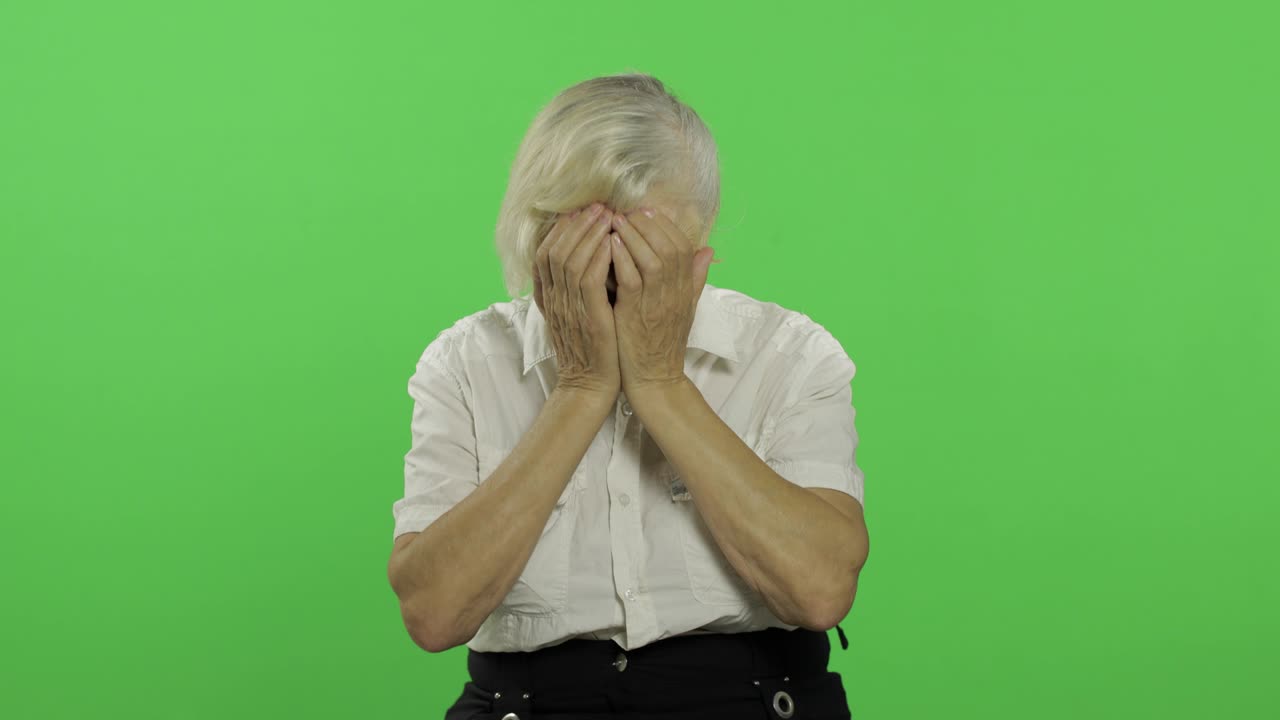 An elderly woman cries. Senior pretty grandmother in a white shirt. Chroma key