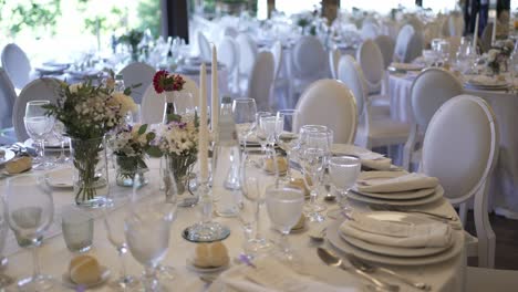 elegantly set wedding reception tables with white decor, glassware, and floral centerpieces