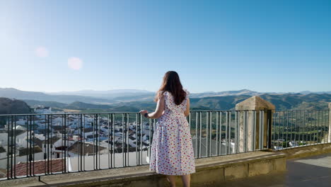 A-Young-Woman-In-White-Dress-Looking-At-The-Whitewashed-Village-Of-Olvera-In-CÃ¡diz,-Andalusia,-Spain