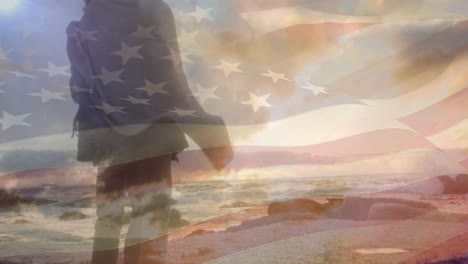 animation of flag of united states of america over couple standing on beach