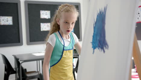 caucasian girl with blonde hair looks surprised in a classroom at school