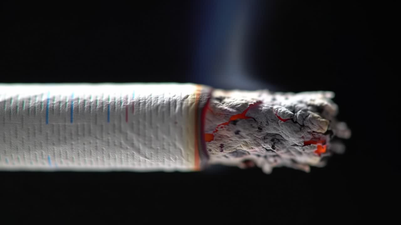 Close-up View of Burning Cigarette Illustrating the Dangers of Smoking Indoors at Nighttime