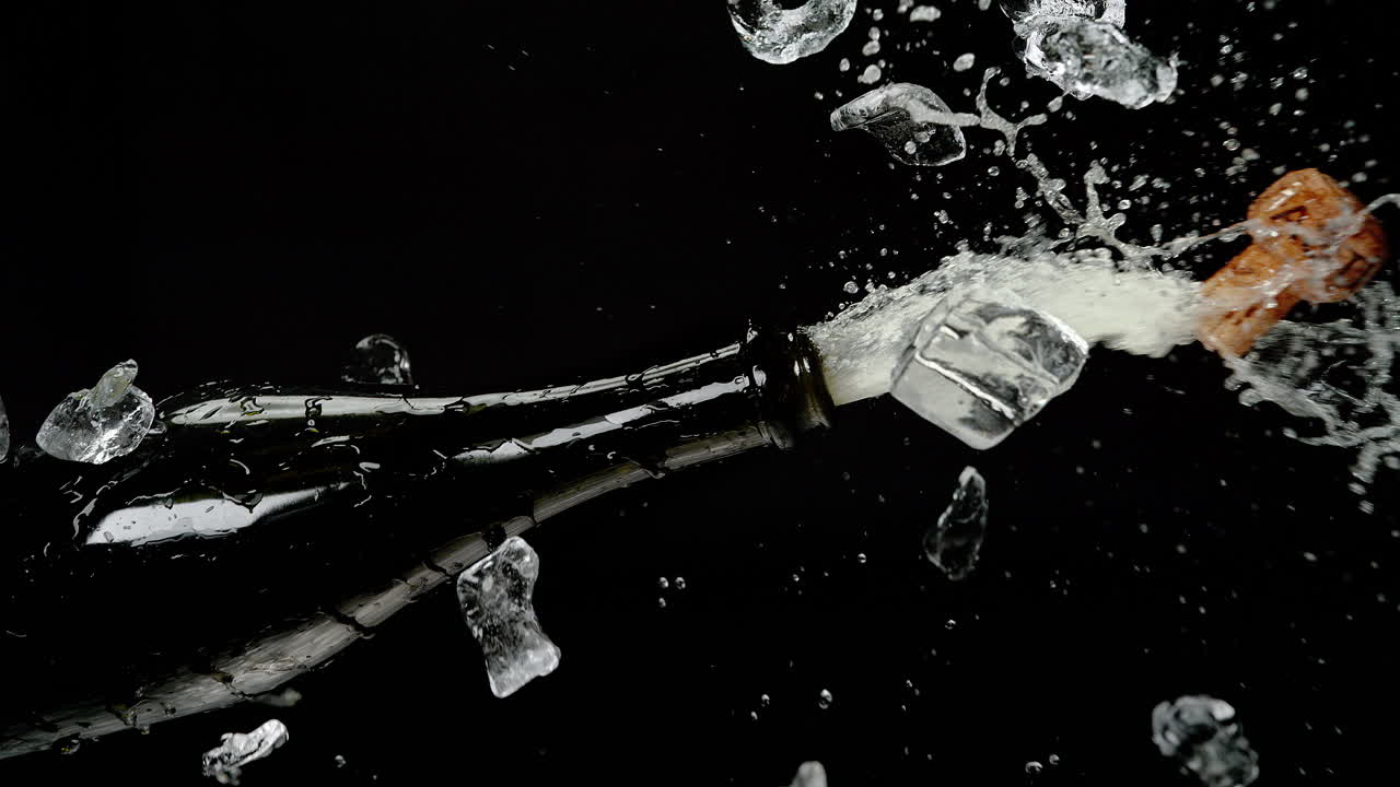 Champagne Bottle Popping out of the Ice Cubes Bucket and Exploding with a Stream of Sparkling Wine on the Black Background in Slow Motion