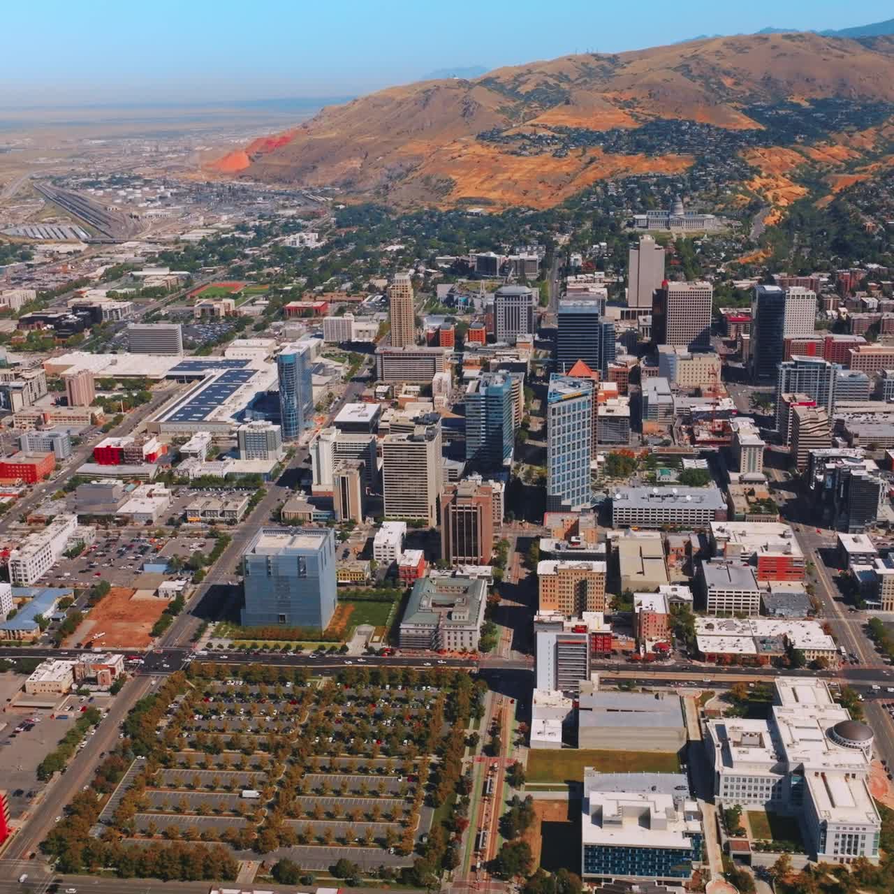 Sunlit scenery of amazing Salt Lake City with varied architecture. Bare mountains of Utah at background. Aerial perspective