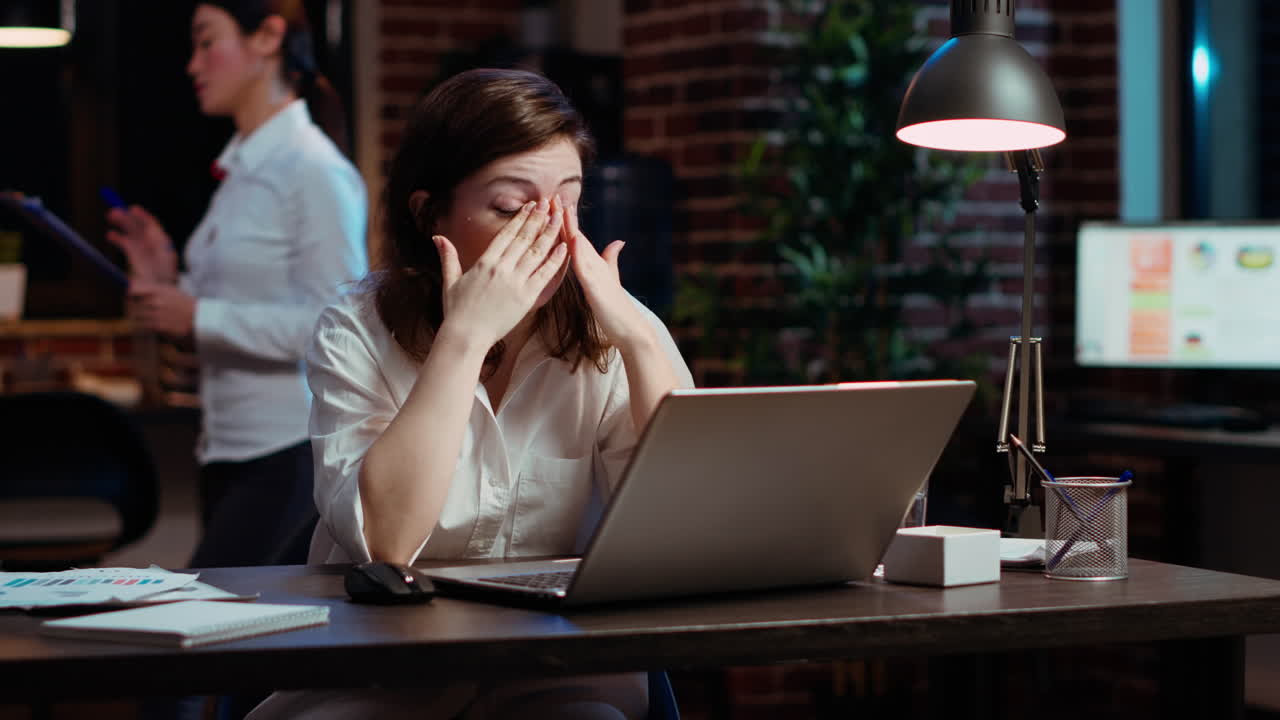 지친 직원이 사무실 책상에서 집중을 유지하기 위해 고군분투하고, 과로감을 느니다.
