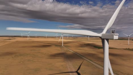 A-drone-flies-backwards-from-a-windmill-on-a-southern-Alberta,-Canada-windfarm