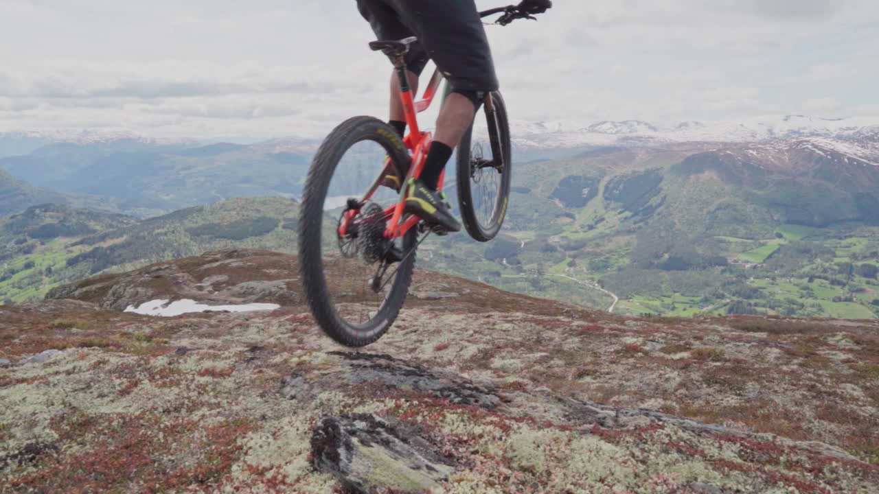 Epic mountain biking adventure above the fjords near Sogndal, Norway. Rider tackles rugged trails surrounded by dramatic cliffs, lush green hills, and stunning Nordic scenery