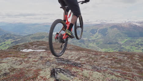 epic mountain biking adventure above the fjords near sogndal, norway. rider tackles rugged trails surrounded by dramatic cliffs, lush green hills, and stunning nordic scenery